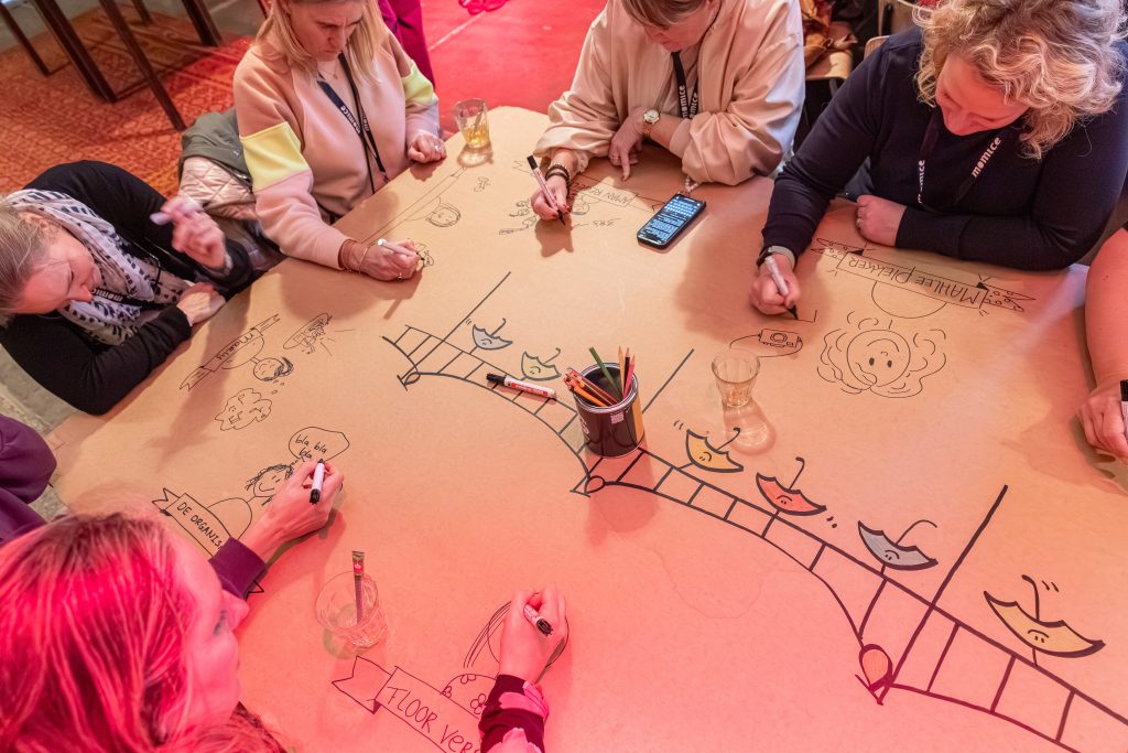 Deelnemers tekenen gezamenlijk aan een grote illustratietafel tijdens een interactieve illustratie workshop en event activatie van Studio Limón.