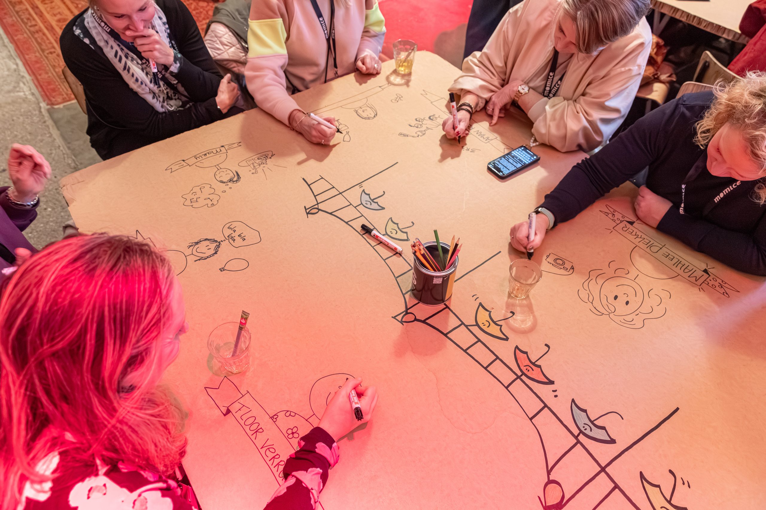 Deelnemers tekenen samen aan een interactieve illustratietafel tijdens een live illustratie workshop en event activatie van Studio Limón.