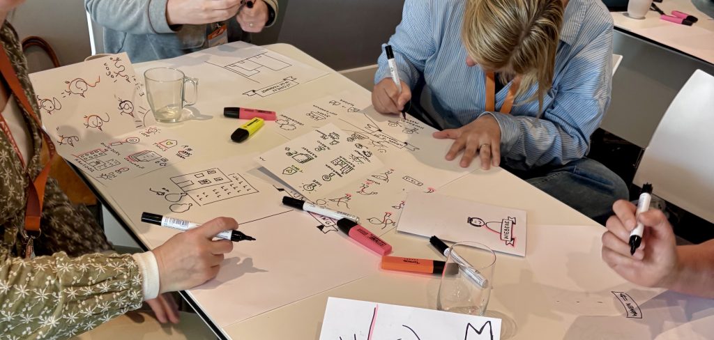 Deelnemers werken in kleine groepjes aan visualisaties tijdens workshop zakelijk tekenen